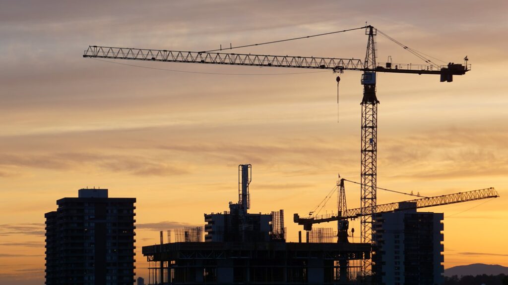 Kyrgyzstan vs UAE vs Saudi Arabia: A 2026 Comparison for Pakistani Recruitment Agencies Construction cranes silhouetted at sunset — comparing Kyrgyzstan to Gulf destinations for recruitment agencies